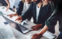 four people collaborating around a laptop