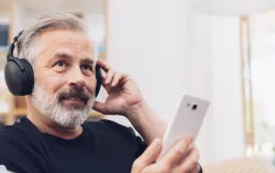 Man with headphones on and holding phone 