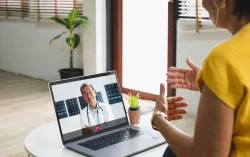 Smiling woman sitting, on Zoom call with clinician 