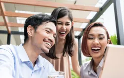 Three people smiling at laptop