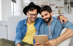 two men sitting close together looking at a tablet device