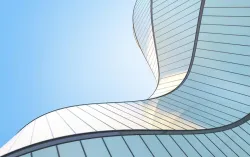 Upwards angle view of an abstract silver wave shape building and blue sky