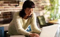 A person standing at a counter working on a laptop