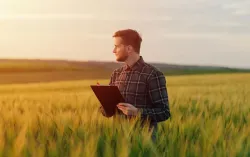 Person stands in a field holding a clipboard