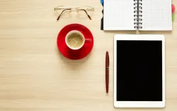 tablette café bloc-notes stylo lunettes sur le bureau