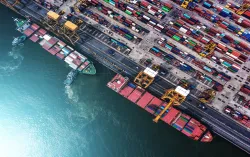 Draufsicht auf einen Hafen mit Frachtschiff und gestapelten Containern, Logistik und globaler Warenverkehr