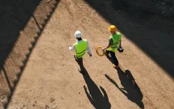 Top view of builders in hardhats and green safety jackets at a construction site