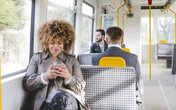 Woman sat on West Midlands Tram looking at her phone