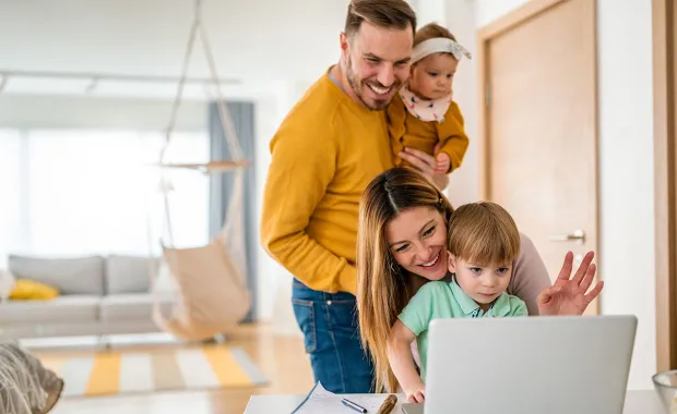 Mum, Dad and two children smiling happily while looking at a computer screen