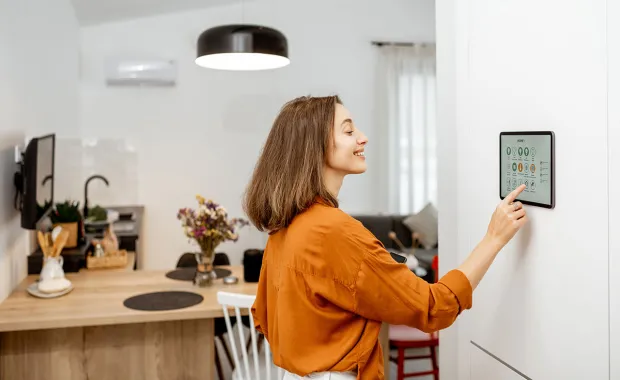 Woman controlling her home smart meter from a screen in a kitchen