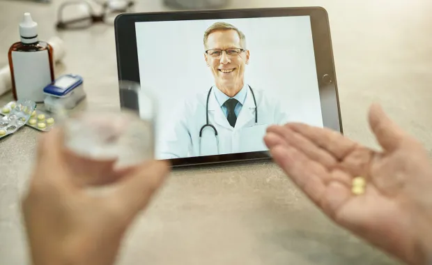 Person taking medication while speaking to their doctor via video call 