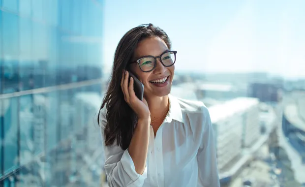 Smiling woman talking on phone with city and high buildings on the background