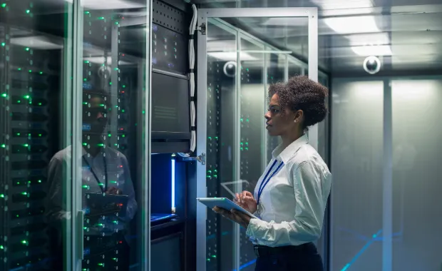 A woman stood in a server room holding a tablet
