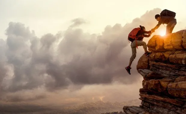 Zwei Bergsteiger helfen sich gegenseitig einen Berg zu erklimmen