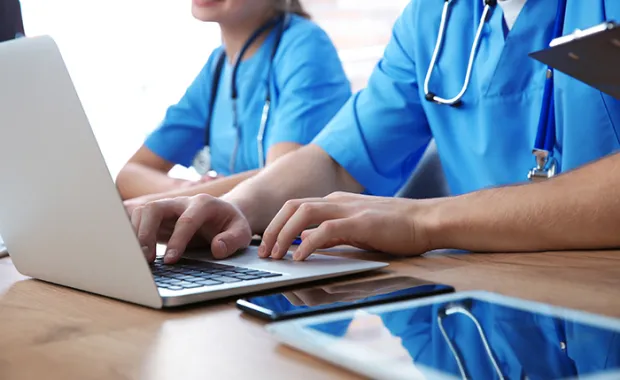 healthcare workers sitting a table typing into a computer 