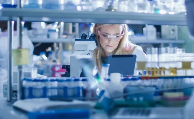 A woman wearing safety goggles works at a laboratory