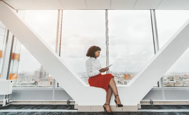 Femme assise dans un espace de travail moderne, utilisant une tablette