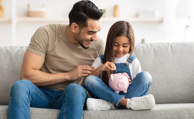 Father and daughter putting money into a piggy bank