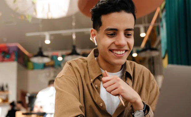 Apprentice smiling at laptop in cafe