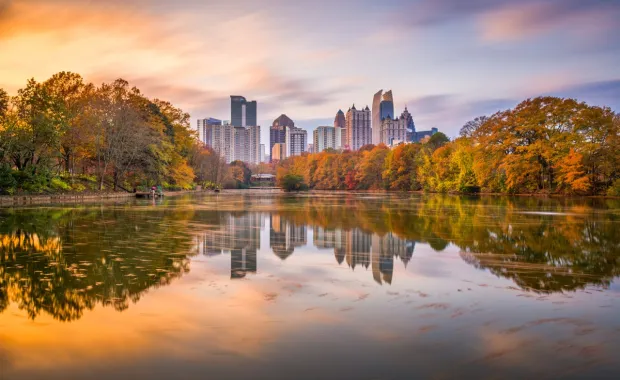 A body of water with trees and buildings in the background with Piedmont Park in the background
