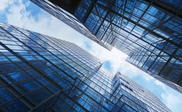 Abstrakte Architekturaufnahme moderner Glasgebäude als Symbol für Transparenz, Struktur und steuerbare Governance in einem länderübergreifenden Justiz-Großprojekt.