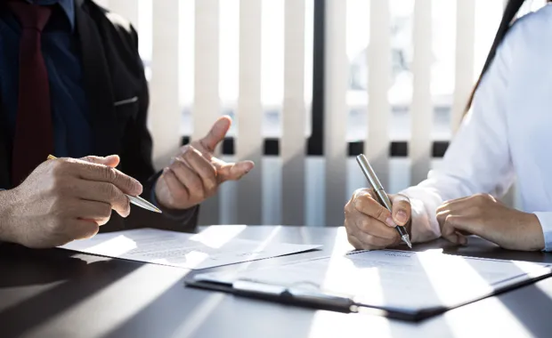 Two people signing a document around insurance
