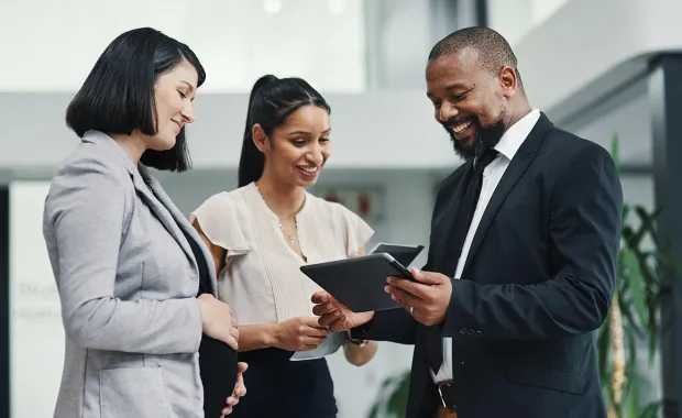 Three cyber security consultants look at tablet device together