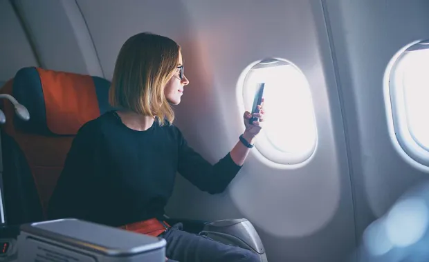Mujer de negocios tomando fotos en el teléfono inteligente mientras está sentada en un avión