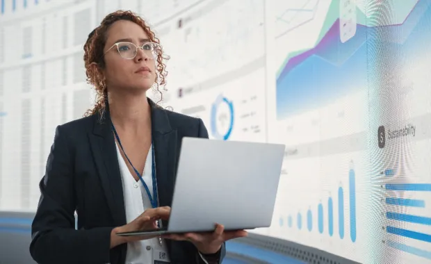 Business analyst reviewing hybrid cloud data dashboards on laptop