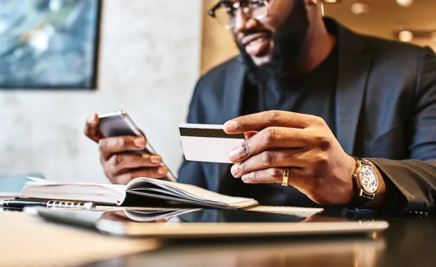 Businessman holding mobile and credit card in cafe