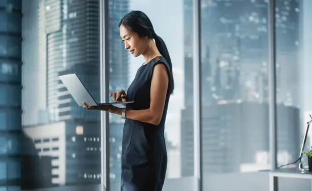 Professional standing and using a laptop