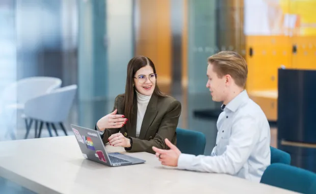 CGI:n konsultit juttelevat toimistossa pöydän ääressa