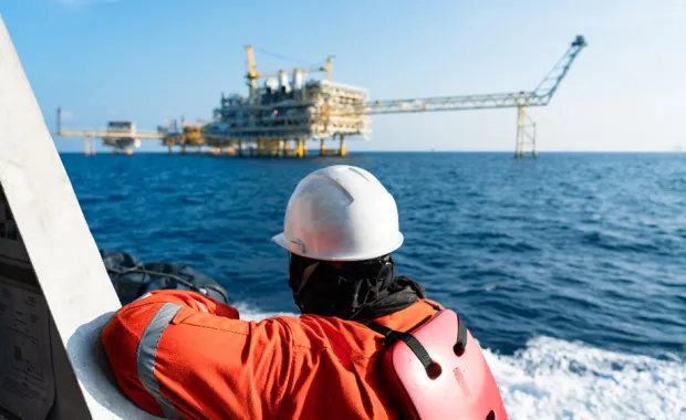 operational worker on the sea looking at an oil rig
