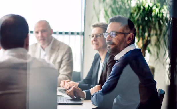 A group of colleagues seated around a conference table during a business meeting
