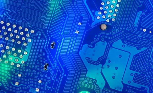 Närbild av ett blått kretskort med elektroniska banor och lödpunkter.