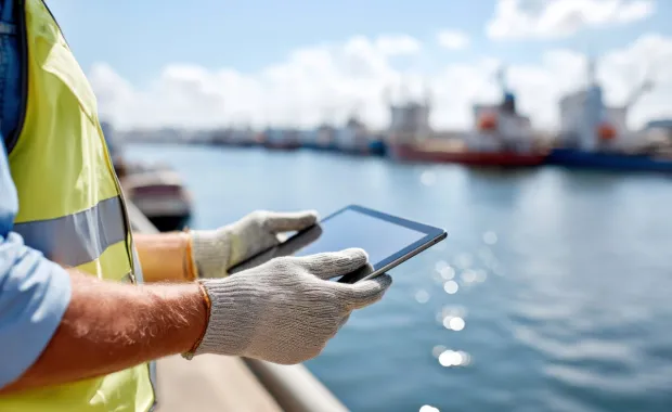 Utilities worker holding a tablet by a river