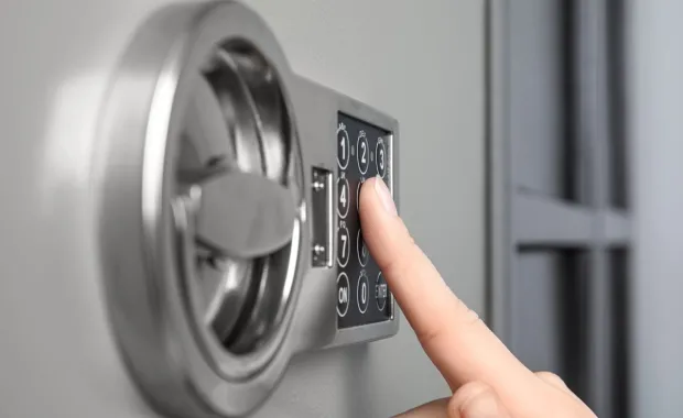 A closeup image of a woman opening a steel safe with an electronic lock