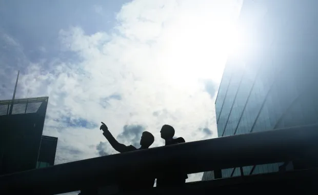 Two professionals pointing at clouds from an office terrace