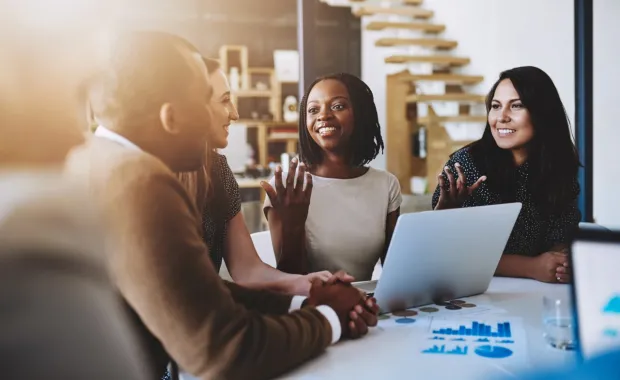 Consultants smile and discuss data on laptop