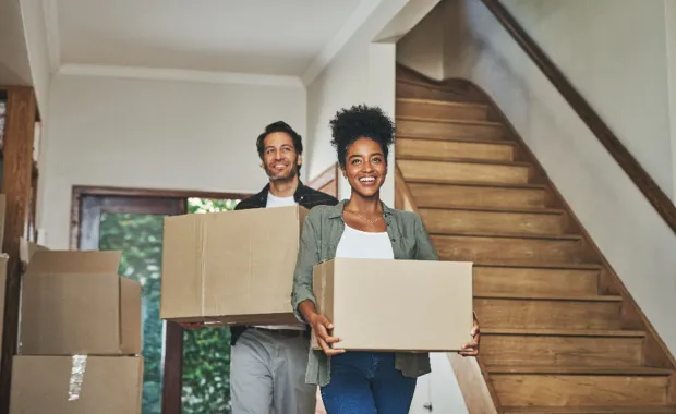 Couple carrying moving boxes into new home