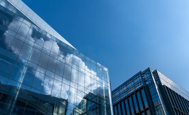 Microsoft - Microsoft-ratkaisut yrityksille. Kuvituskuva: pilvet heijastuvat toimistorakennuksen ikkunasta.