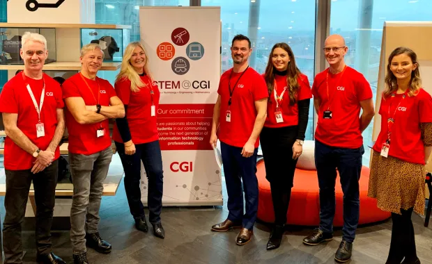 CGI Volunteers standing in front of a STEM Camp banner