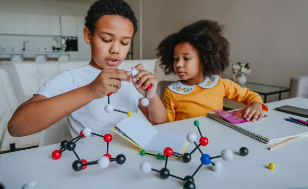 Två barn sitter vid köksbordet och gör sin vetenskapsläxa