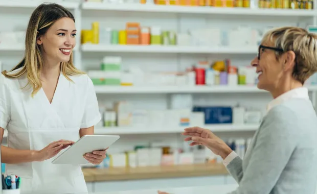 Pharmacien et client discutant au comptoir d’une pharmacie