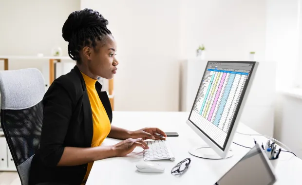 Professional analyzing data on a large monitor at her desk