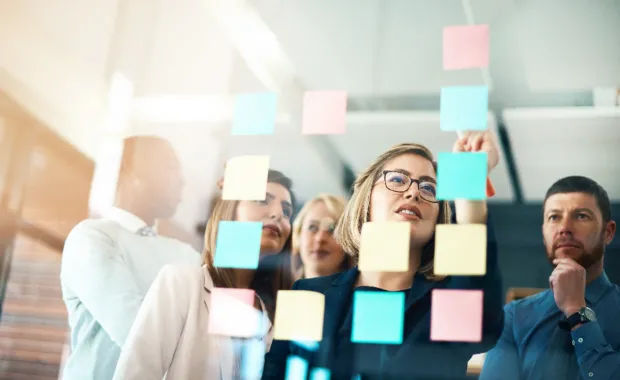 Führungsteam analysiert Change-Trigger und Wirkungsketten an einer Glaswand im Rahmen eines Change-Management-Workshops.