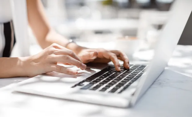 Händer på ett tangentbord på en laptop