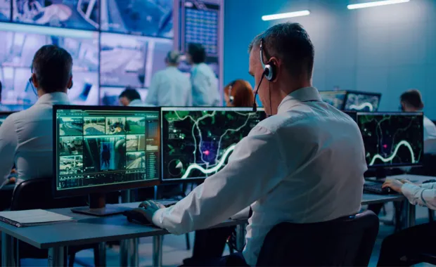 Defence consultant working at dual monitors in control room
