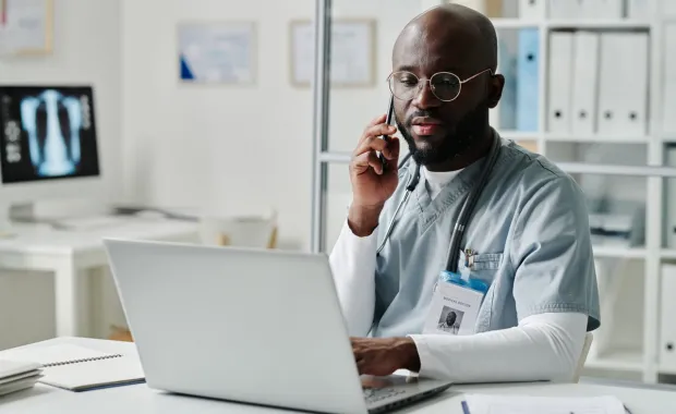 Doctor on phone looking at laptop