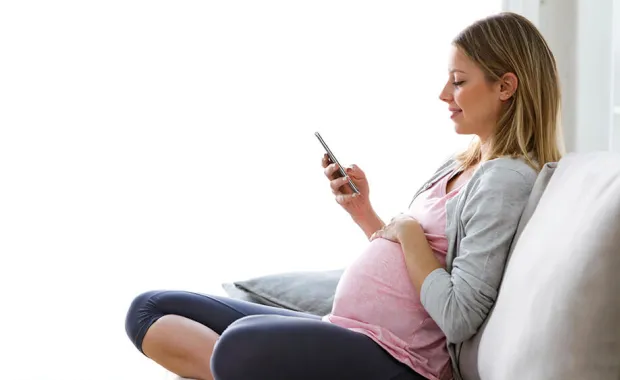 Pregnant woman relaxed and watching her mobile
